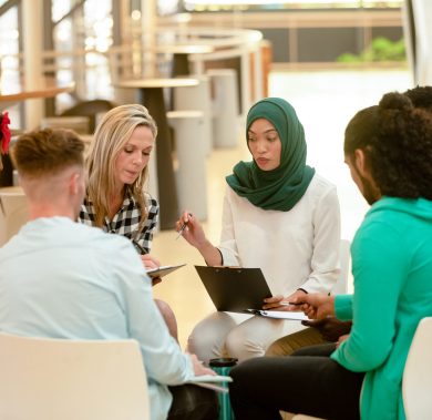 Front view of diverse business people sitting together and having a group discussion in a modern office